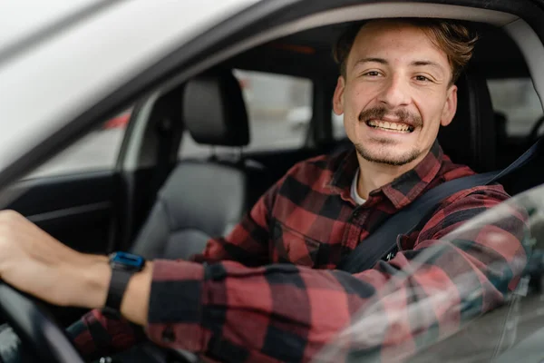 one man caucasian male with brown hair and mustaches sitting in a car adult driver wear shirt while driving automobile travel transport concept real people copy space happy smile