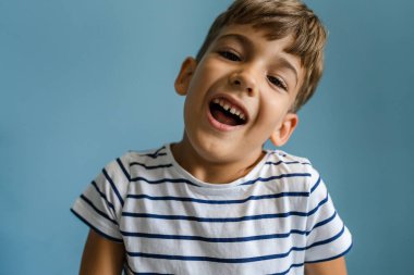 Kafkasyalı bir çocuk mavi duvarın önünde evde aylak aylak dolaşıp çocukluk portresi çiziyor.