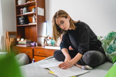 One caucasian woman female student study while lying in bed at home