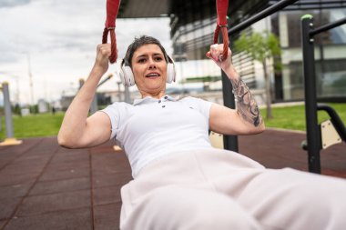 Bir kadın olgun ya da yaşlı, kauçuk elastik direnç bantlı beyaz kadın eğitimi. Açık spor salonunun spor salonundaki tüplerde. Sağlıklı yaşam tarzı konsepti.