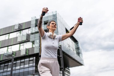 Bir kadın olgun ya da yaşlı, kauçuk elastik direnç bantlı beyaz kadın eğitimi. Açık spor salonunun spor salonundaki tüplerde. Sağlıklı yaşam tarzı konsepti.