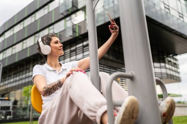 Yetişkin ya da yaşlı bir kadın, spor salonunun parkındaki basın fitness makinesinde spor fotoğraflarının çekildiği sağlıklı yaşam tarzı konseptini taklit ediyor.