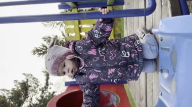 Bir kız çocuğu iki yaşında parkta oynuyor. Sadece kış ya da sonbahar günü oyun parkında kaydırağa tırmanıyor. UGC kullanıcısı içeriği dikey video üretiyor.