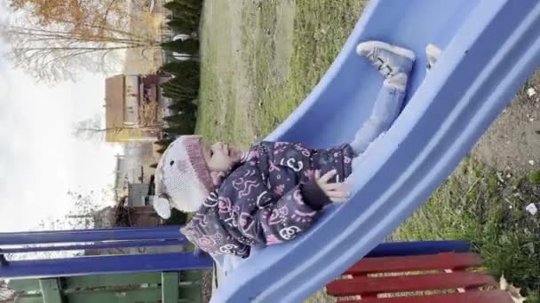 冬や秋の日だけで遊び場でスライダーに登って公園で遊んで2歳の1人の女の子幼児Ugcユーザーが生成されたコンテンツ垂直ビデオ現実の人々 — ストック動画