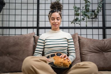 Genç beyaz bir kadın kahvaltıda ev yapımı kruvasan pişirerek evde oturuyor. Rutin insanlar fotokopi alanı kavramını benimsiyor.