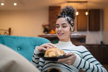 Genç beyaz bir kadın kahvaltıda ev yapımı kruvasan pişirerek evde oturuyor. Rutin insanlar fotokopi alanı kavramını benimsiyor.