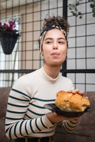 One woman young caucasian female sit at home having baked homemade croissant for breakfast morning routine real people concept copy space