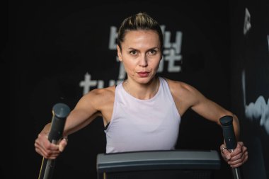 Beyaz tenli olgun bir kadın evde ya da spor salonunda Eliptik Çapraz Eğitiminde egzersiz yapıyor. Sağlıklı yaşam tarzı ve sağlık konsepti.