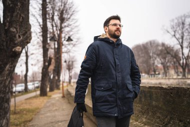 one caucasian man standing alone in autumn day holding a business bag laptop real people young businessman going to work