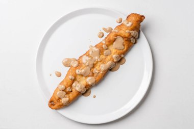 Top down on fried dough stick in white plate Mekitsa or mekika traditional serbian bulgarian and macedoinan dish made of kneaded dough