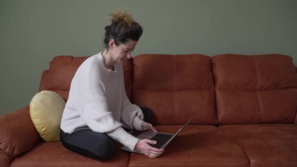 Одна Взрослая Кавказка Сидит Дома Диване Работает Ноутбуком Просматривает Интернет — стоковое видео