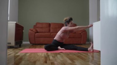 one woman caucasian female doing yoga pose stretching on the mat on the floor at home daily routine self care concept relaxation practice sequence well-being 