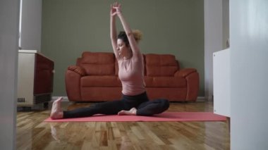 one woman caucasian female doing yoga pose stretching on the mat on the floor at home daily routine self care concept relaxation practice sequence well-being 