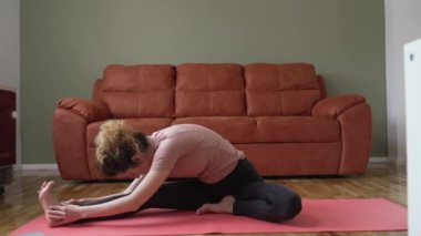 one woman caucasian female doing yoga pose stretching on the mat on the floor at home daily routine self care concept relaxation practice sequence well-being 