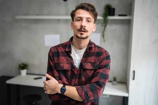 One man young adult caucasian male standing at office at work with brown hair mustaches and beard looking to the camera arms crossed confident real people copy space
