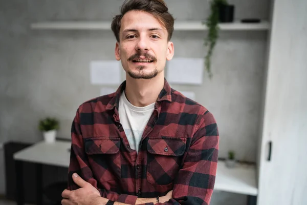 One man young adult caucasian male standing at office at work with brown hair mustaches and beard looking to the camera happy smile confident real people copy space