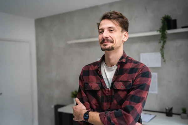 One man young adult caucasian male standing at office at work with brown hair mustaches and beard looking to the side happy smile confident real people copy space