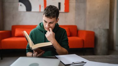 one young man caucasian teenager student learning study reading book while sitting at home prepare exam or work on project real people education concept copy space