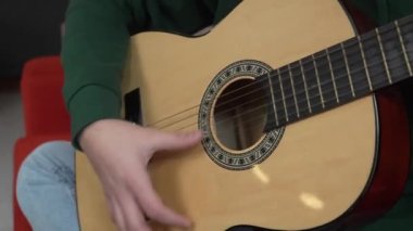 One young man Caucasian teenager sit at home in room playing guitar