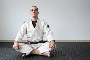 brazilian jiu jitsu BJJ black belt instructor professor at the academy sitting on the tatami mats