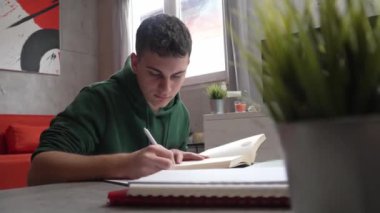 one young man caucasian teenager student learning study reading book while sitting at home prepare exam or work on project real people education concept