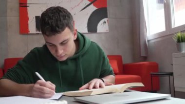 one young man caucasian teenager student learning study reading book while sitting at home prepare exam or work on project real people education concept