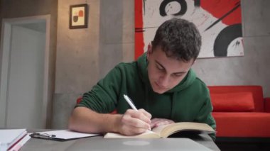 one young man caucasian teenager student learning study reading book while sitting at home prepare exam or work on project real people education concept
