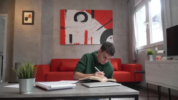 1人の若い男白人の10代の学生家庭で試験の準備やプロジェクトの仕事に座って読書本を学ぶ実際の人々の教育の概念 — ストック動画