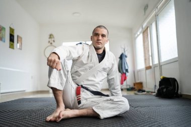 brazilian jiu jitsu BJJ black belt instructor professor at the academy sitting on the tatami mats