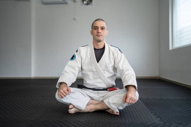 brazilian jiu jitsu BJJ black belt instructor professor at the academy sitting on the tatami mats
