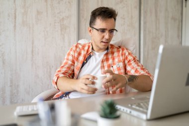 One caucasian man sitting at office at work working on laptop computer in day young freelance or entrepreneur businessman online business copy space young adult finishing or beginning confident think