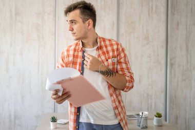 Bir erkek Kafkas girişimci işadamı masabaşında duruyor. Kağıt belgelerini kontrol ediyor ya da gerçek insanları analiz ediyor.