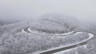 Car drive in snow winter day on the road in mountain range aerial view