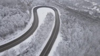 Car drive in snow winter day on the road in mountain range aerial view