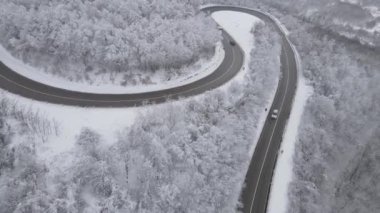 Car drive in snow winter day on the road in mountain range aerial view