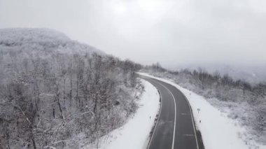 Car drive in snow winter day on the road in mountain range aerial view