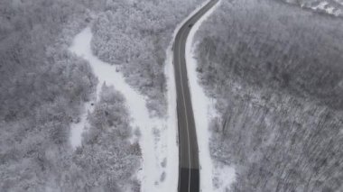 Car drive in snow winter day on the road in mountain range aerial view