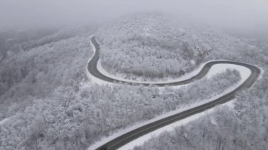 Car drive in snow winter day on the road in mountain range aerial view