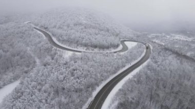 Car drive in snow winter day on the road in mountain range aerial view