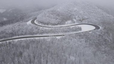 Car drive in snow winter day on the road in mountain range aerial view