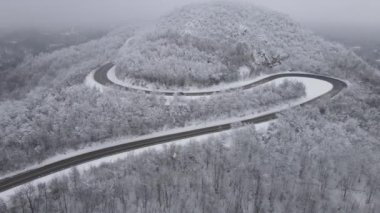 Car drive in snow winter day on the road in mountain range aerial view