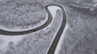 Car drive in snow winter day on the road in mountain range aerial view
