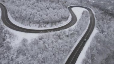 Car drive in snow winter day on the road in mountain range aerial view