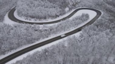 Car drive in snow winter day on the road in mountain range aerial view