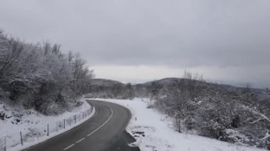 Car drive in snow winter day on the road in mountain range aerial view