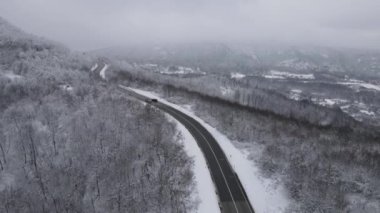 Car drive in snow winter day on the road in mountain range aerial view