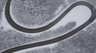 Car drive in snow winter day on the road in mountain range aerial view