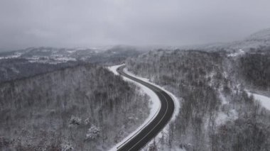 Car drive in snow winter day on the road in mountain range aerial view