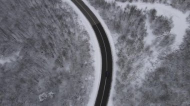 Car drive in snow winter day on the road in mountain range aerial view