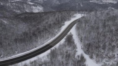 Car drive in snow winter day on the road in mountain range aerial view